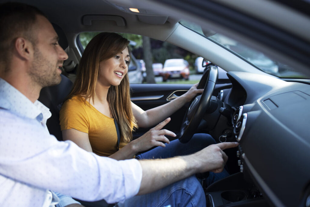 driving instructor showing vehicle dashboard buttons student taking driving lessons 1